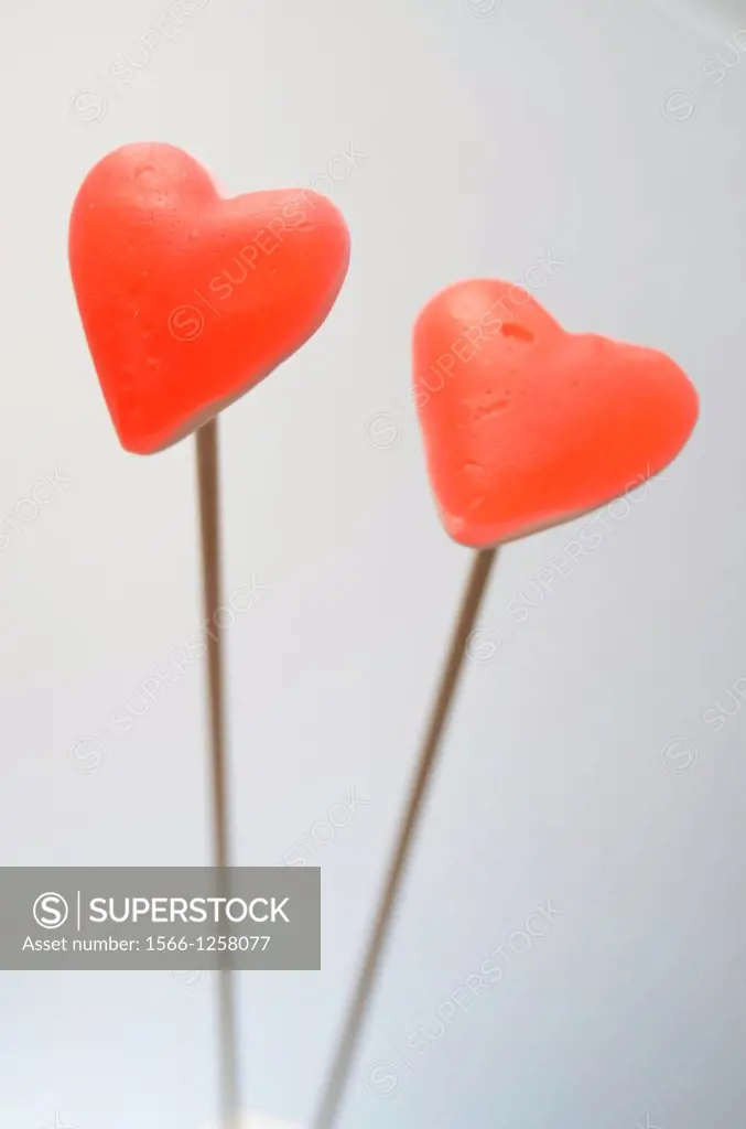 Two red hearts over wooden poles, gray background.