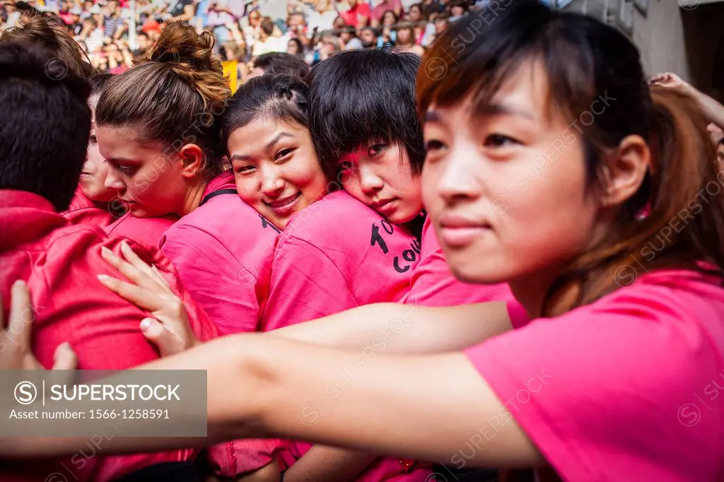 Chinese members of Colla Vella Xiquets de Valls ´Castellers´ building human tower, a Catalan tradition Biannual contest  bullring Tarragona, catalonia...