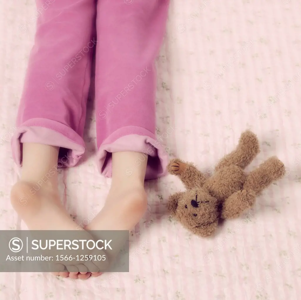 female feet in pink pyjamas with a teddy bear