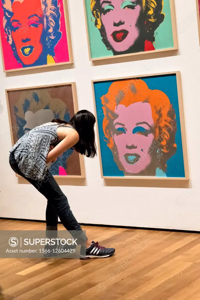 Young Woman Bending Over to Closely Inspect one of Andy Warhol´s Marilyn Monroe Paintings at the Museum of Modern Art, New York City.