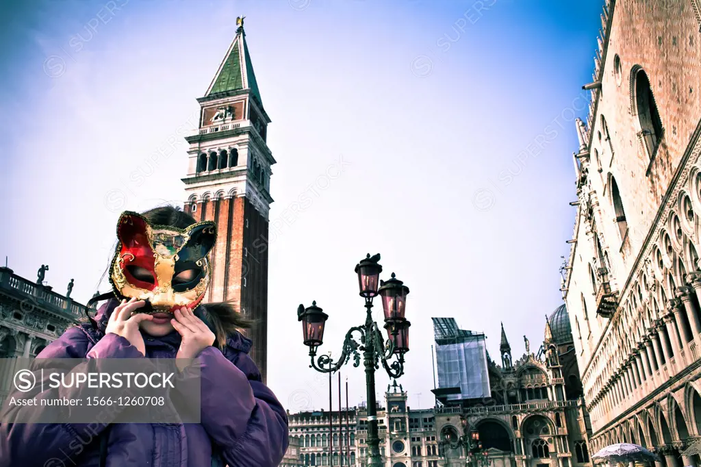 Girl playing with mask at St Marco Square Venice Italy. Doge´s Palace, Church of San Giorgio Maggiore, Piazza San Marco or St. Mark´s Square.