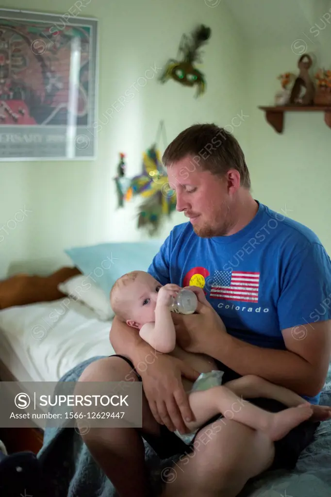 Detroit, Michigan - Man feeds milk to his 11-month-old son.