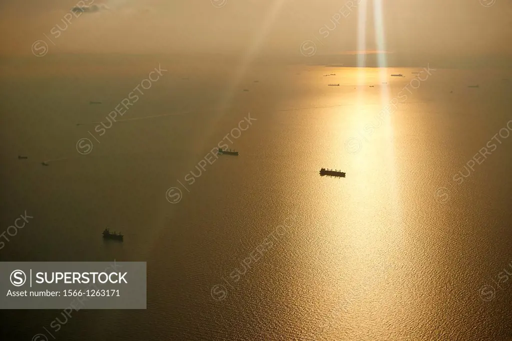 Freight ships sail in the ocean on a bright orange warm day