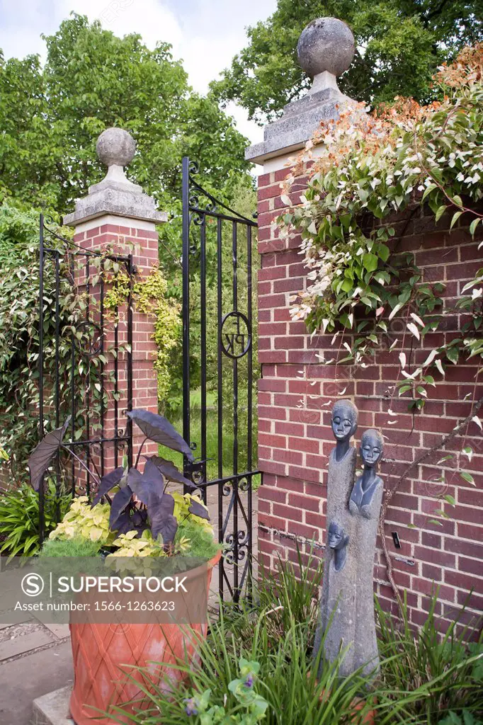 Iron gate in brick wall and pillar with ball finial. Wisley Garden Surrey England.