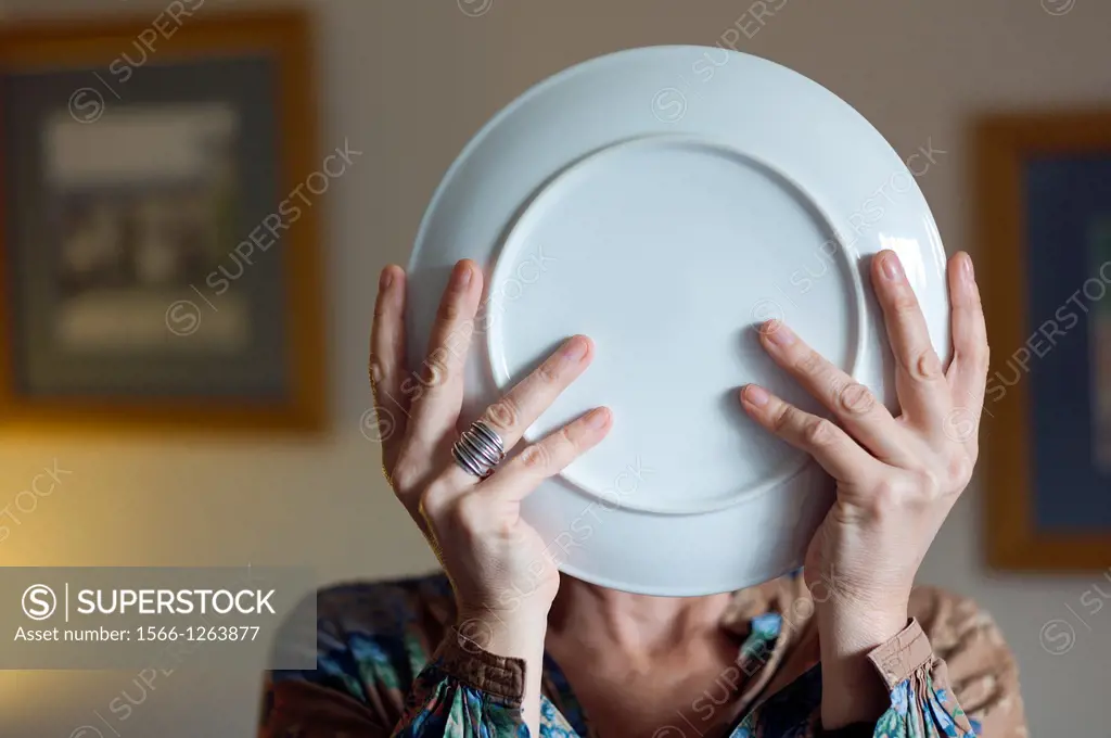 Woman with plate in hands covering her face