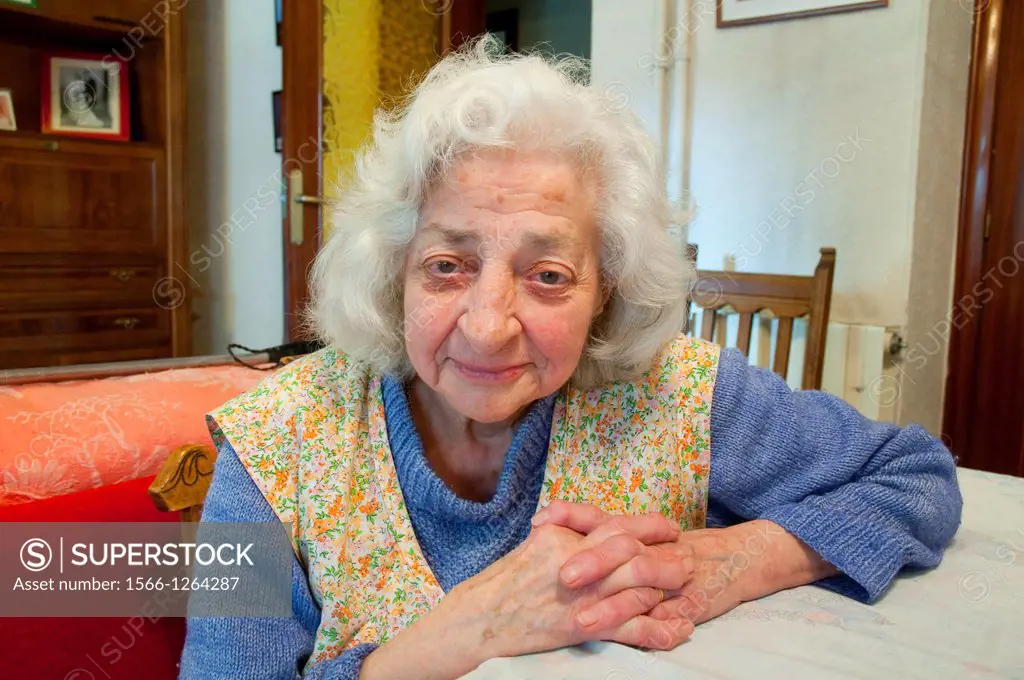 Portrait of elderly woman at home, smiling and looking at the camera