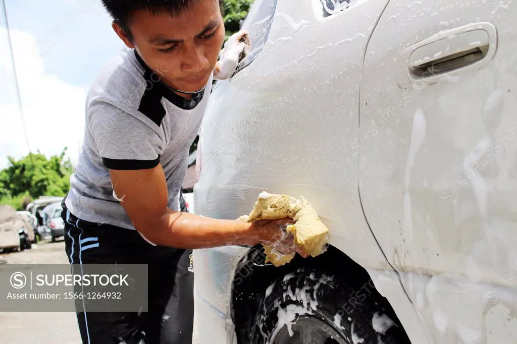 Young couple washing car with a sponge