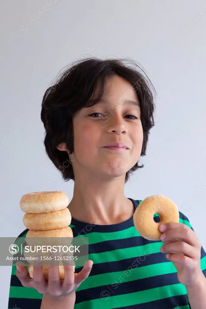 Teenage boy with a pil of donuts on his hand.