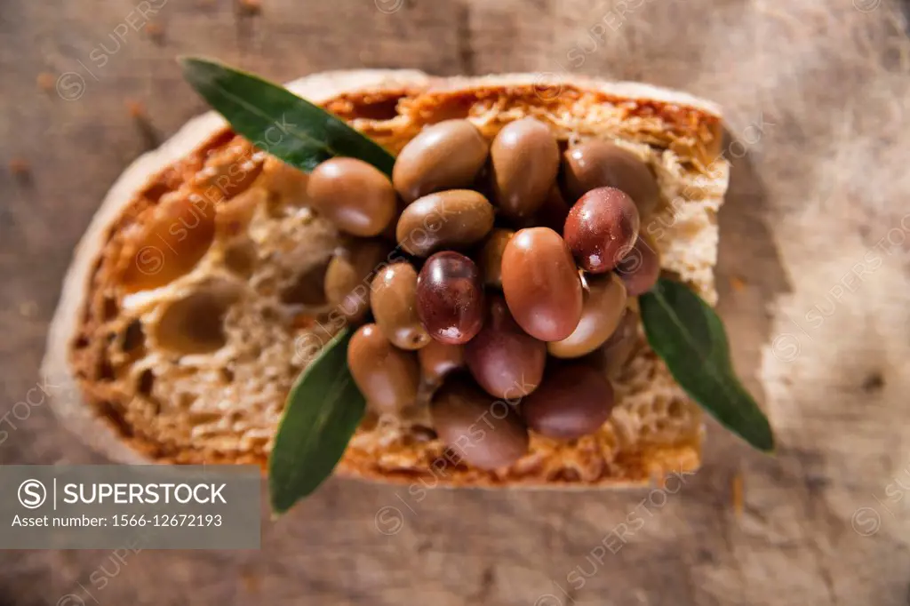 Snack of slice of bread with olives in brine.