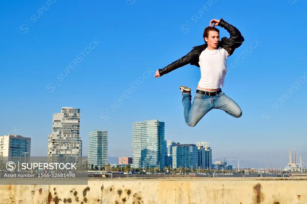 Young man jumping against city skyline. Barcelona, Catalonia, Spain.