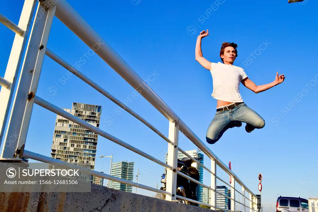 Young man jumping over an iron railing, Barcelona, Catalonia, Spain.