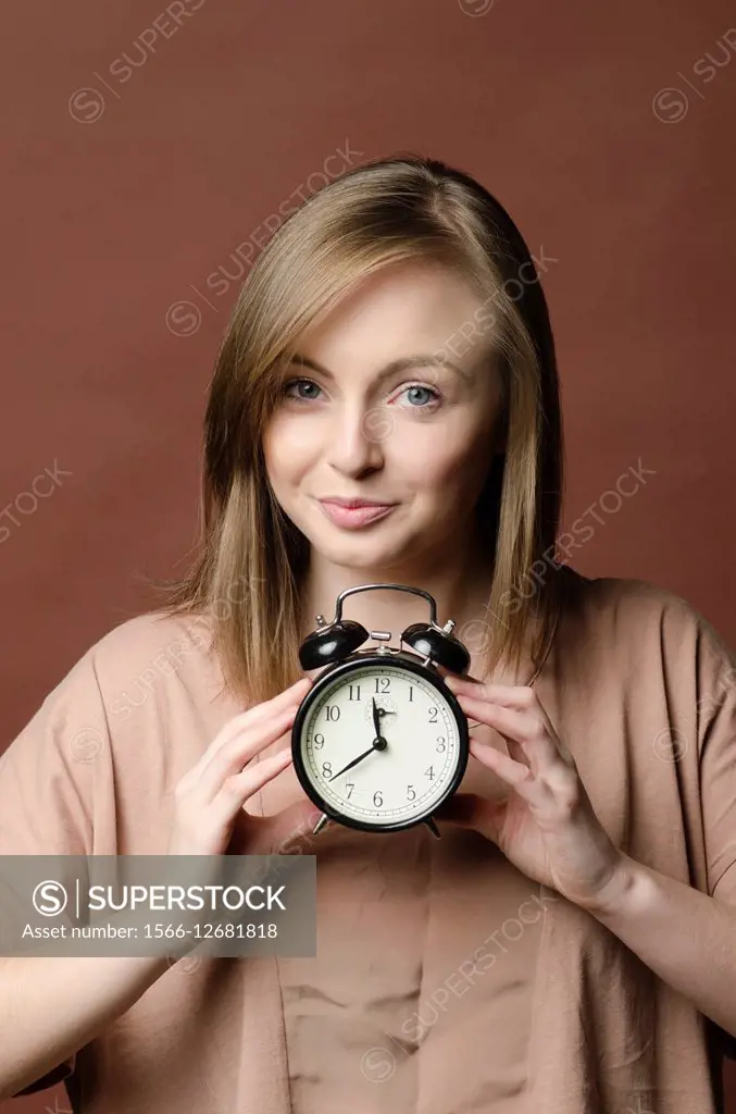 Punctual young woman holding an alarm clock.