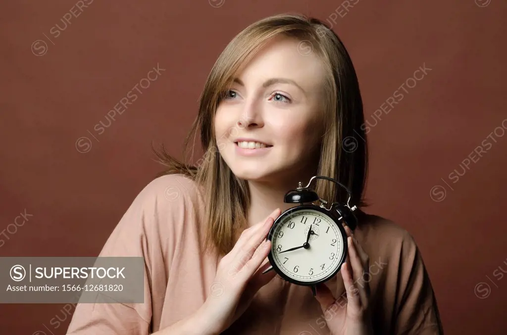 Punctual young woman holding an alarm clock.