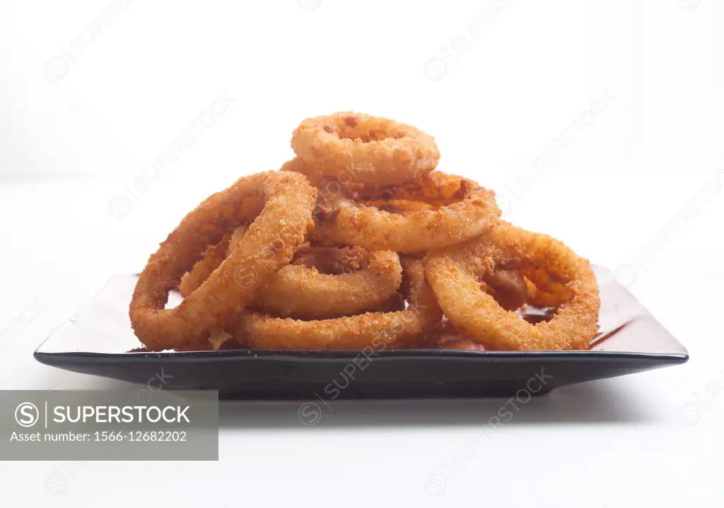 Plate of fried onion rings on white background
