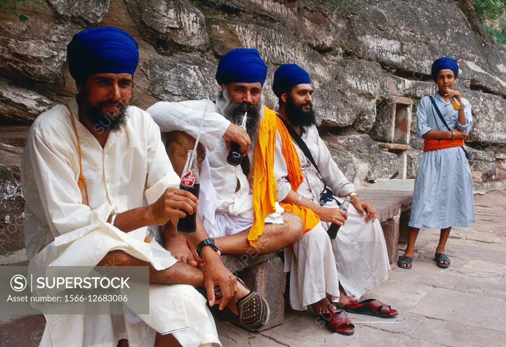 Sikh men traditionally dressed are enjoying soft drinks. At Jodhpur, India. They are visiting the Mehrangarh fort.