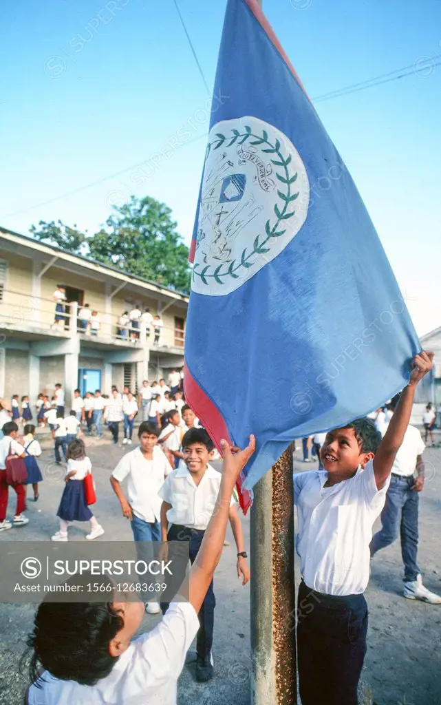 Young boys in school hanging the flag of Belize.