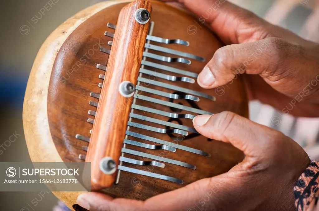 Close-up of African American hands playing a lamellophone musical instrument.