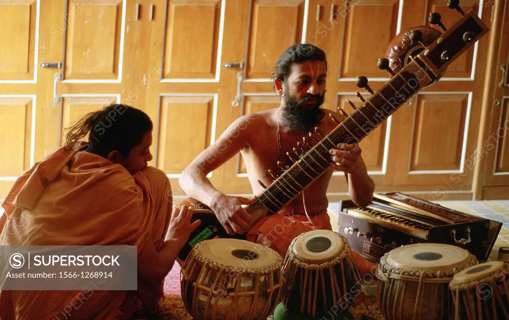 A hindu monk is playing sitar while a novice monk is listening. Gujarat state, India. Both belong to the Swaminarayan sect.