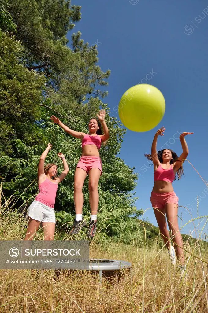 Three girls exercising with fitness ball at field