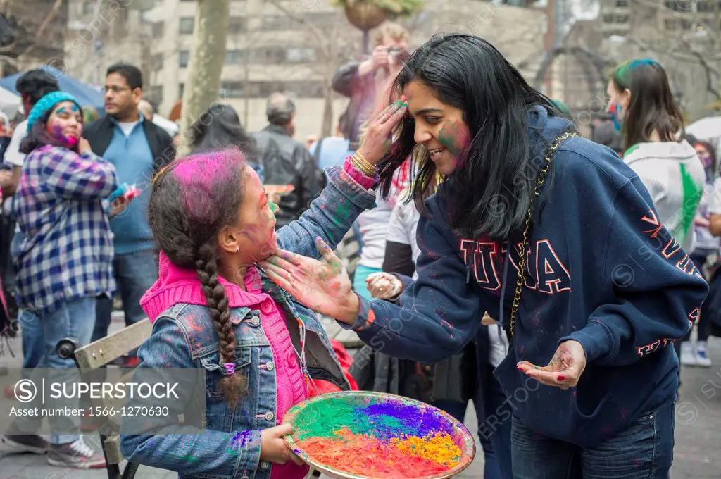 Colored powder is applied to the faces of participants as they celebrate the Indian holiday of Holi at a street festival in Dag Hammarskjold Plaza in ...