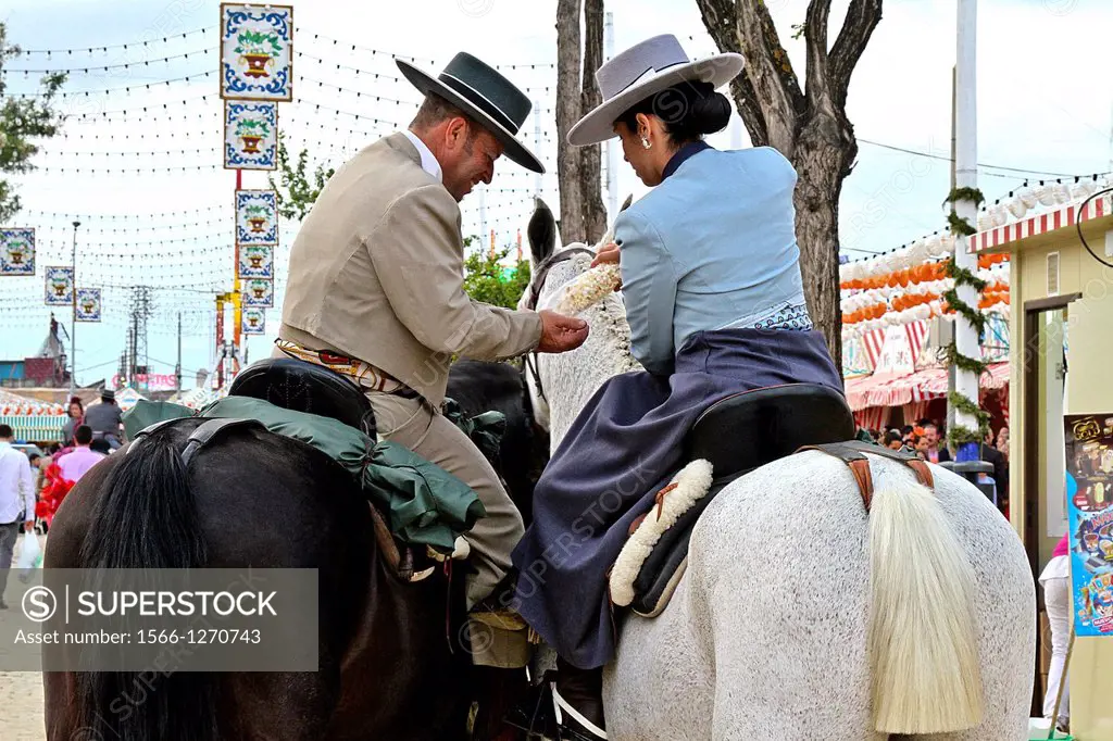 Couple wearing a traditional costumes on a horse at April Fair, Seville, Spain