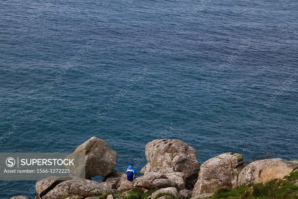 A pilgrim resting at the end of Way of Sant James in Finisterre, Spain