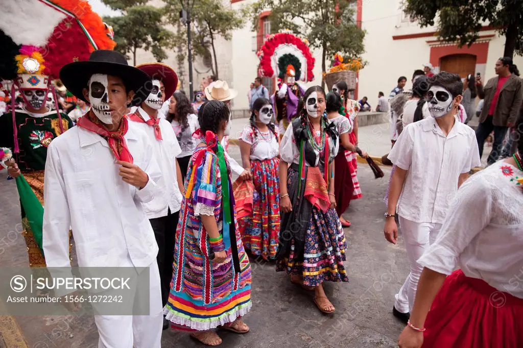 Day of the Dead parade with participants in costumes and spectators in Oaxaca, Mexico.