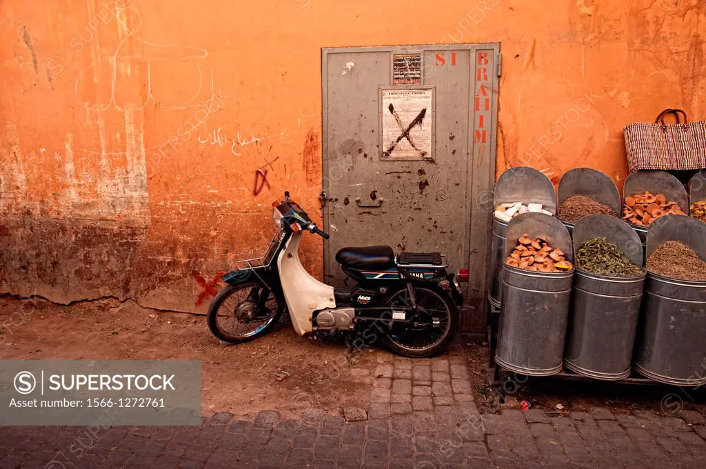 Motorbike parked and traditional products shop in Marrakech medina, Morocco.