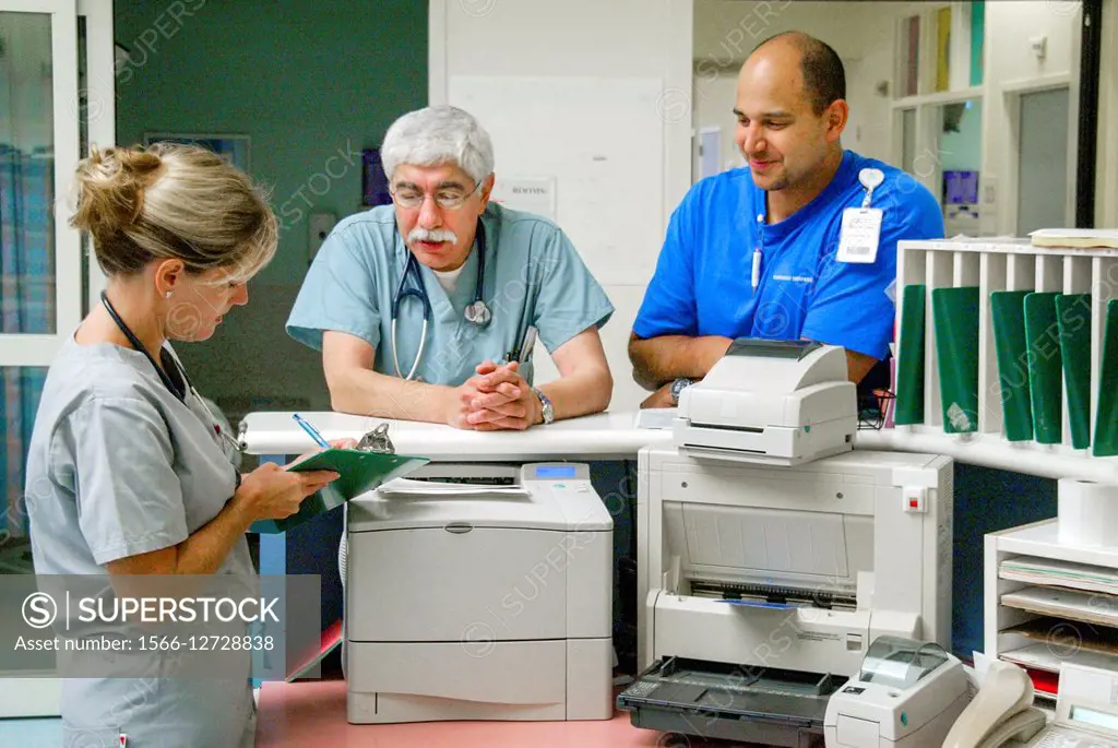 A doctor and a medical technician instruct a nurse in an Orange, CA, hospital emergency room nurse station.