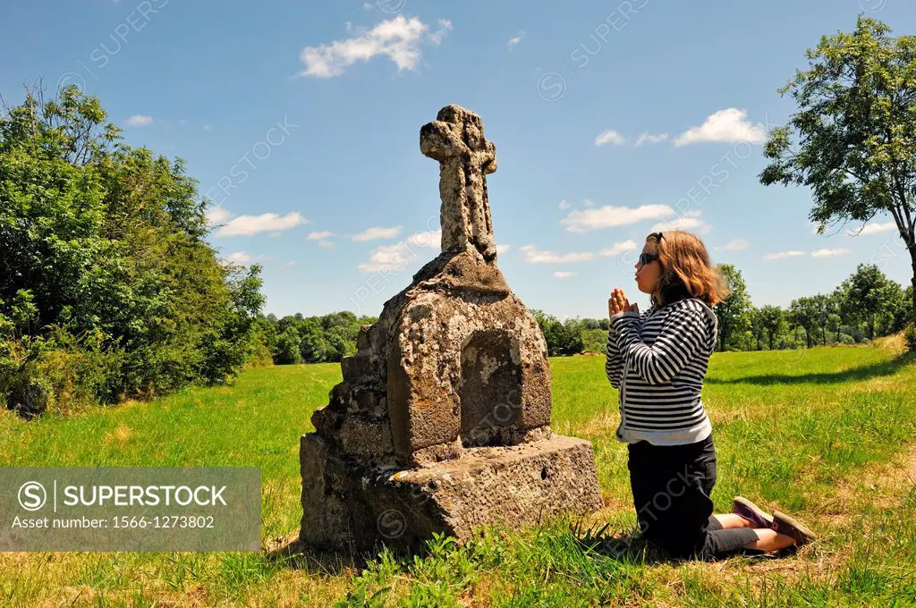 little girl in meditation in front of a stone cross, Cantal department, Auvergne region, France, Europe
