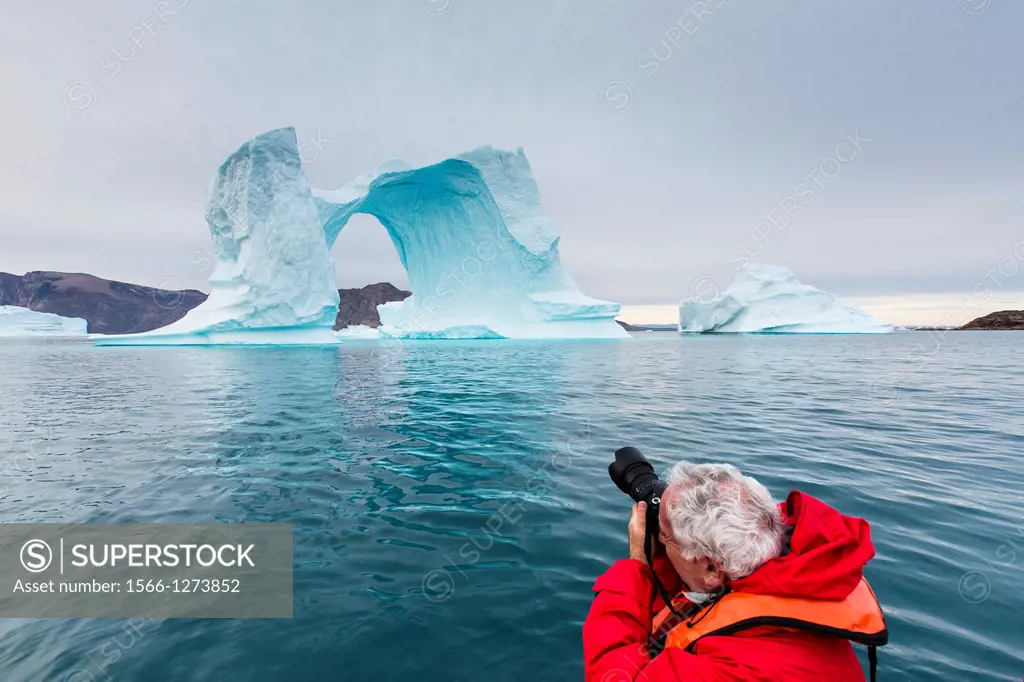 Photographer with huge icebergs in Scoresbysund, Northeast Greenland