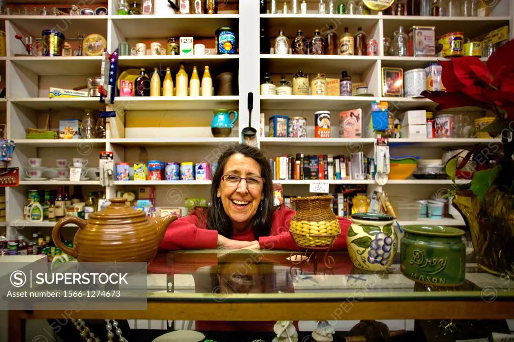 The proprietor of an old fashioned general store poses with shelves of her merchandise in Volcano, CA.