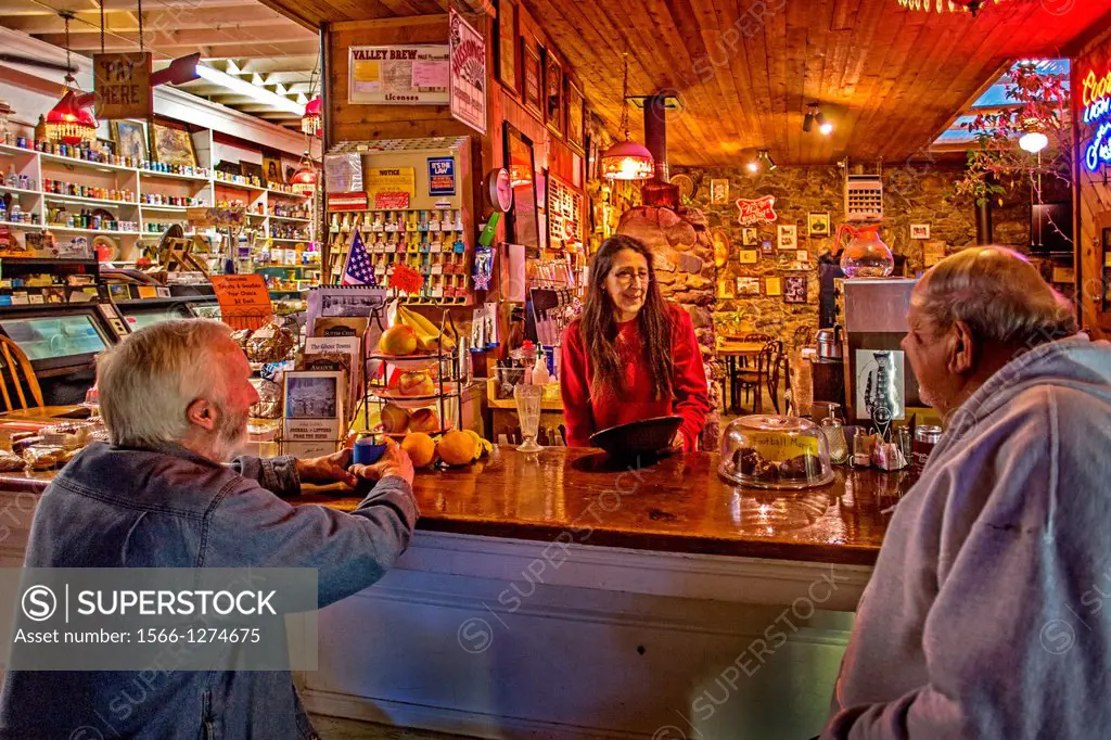 The proprietor of an old fashioned general store chats with two of her customers at the snack bar in Volcano, CA.
