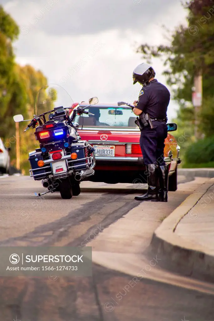 A motorcycle policeman writes a ticket at a traffic stop in Orange, CA.