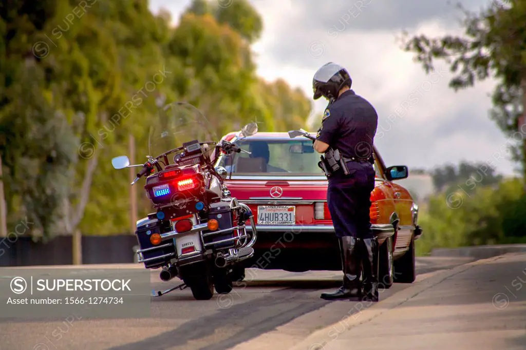 A motorcycle policeman writes a ticket at a traffic stop in Orange, CA.