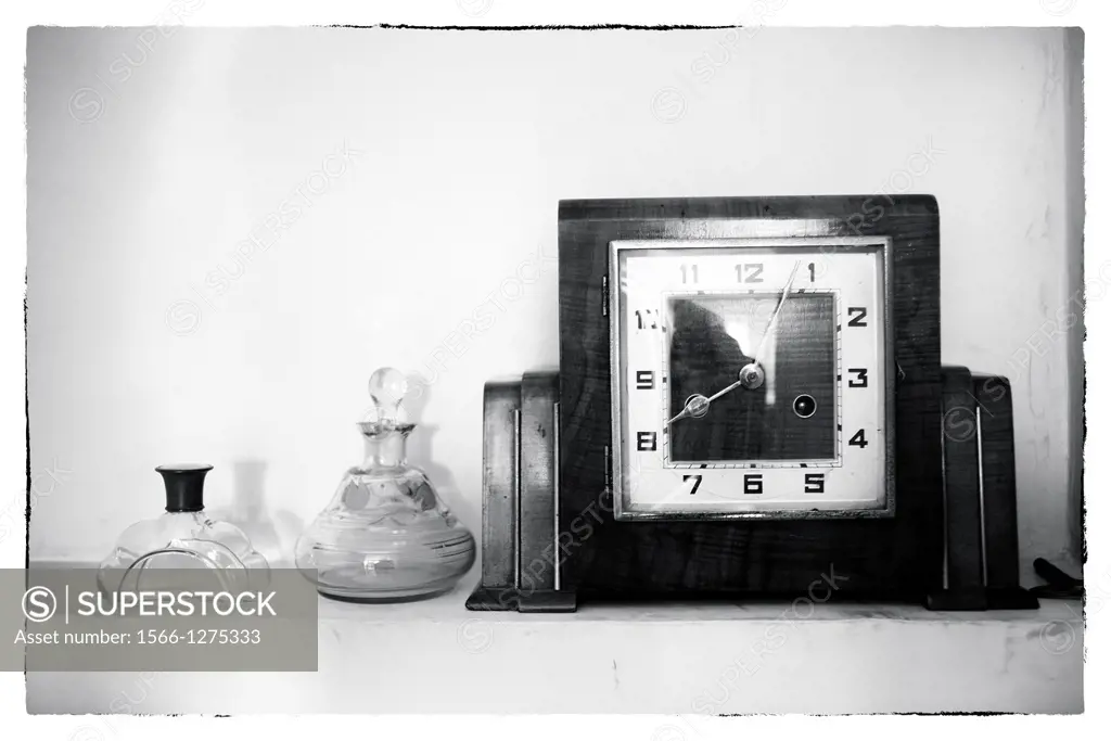 time clock on a shelf with two old perfume bottles