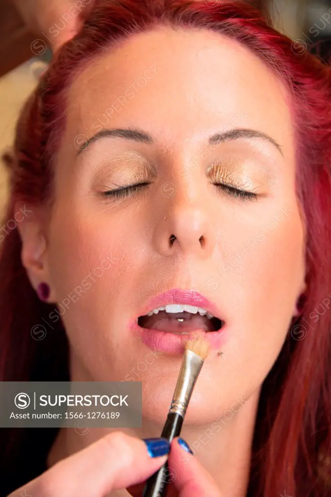 A make-up artist applies lip color to her client.