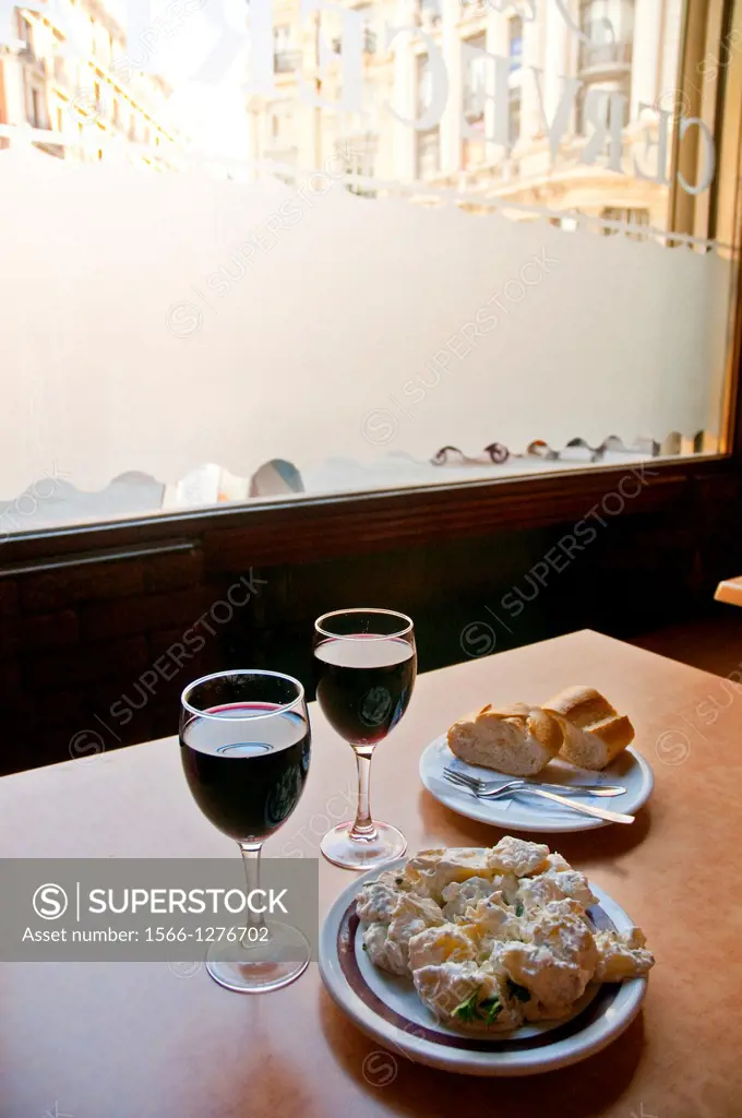Spanish appetizer:alioli potatoes serving and two glasses of wine. Madrid, Spain.
