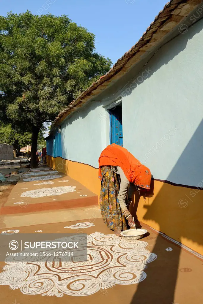 India, Rajasthan, Tonk region, Woman painting a floor Mandana with chalk powder.