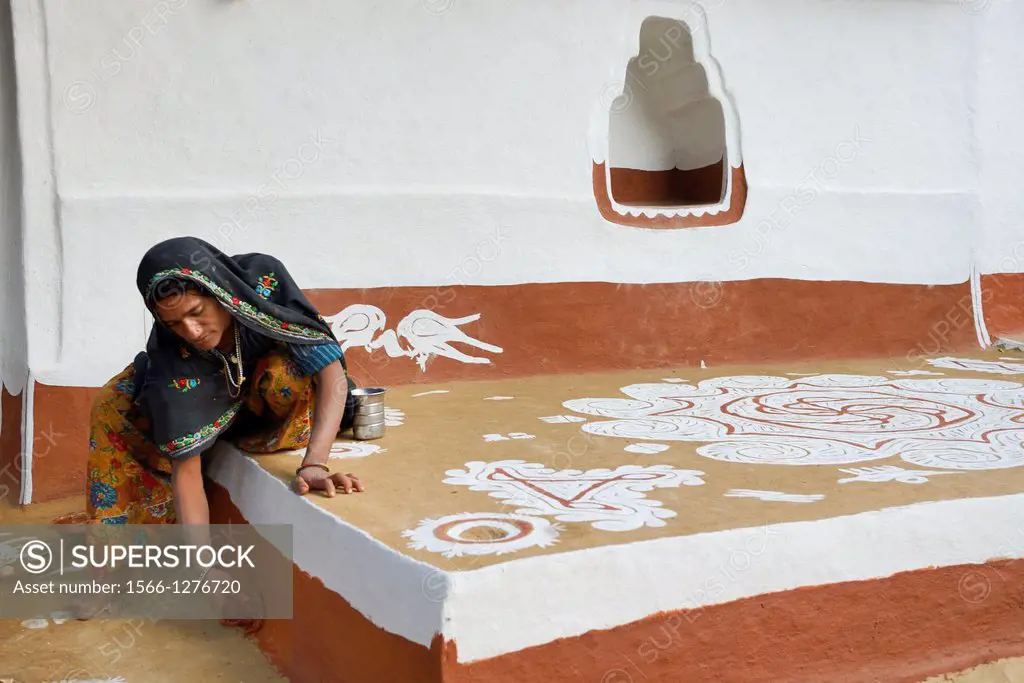 India, Rajasthan, Tonk region, Woman refurbishing her home with a coat of fresh clay prior to Diwali festival.