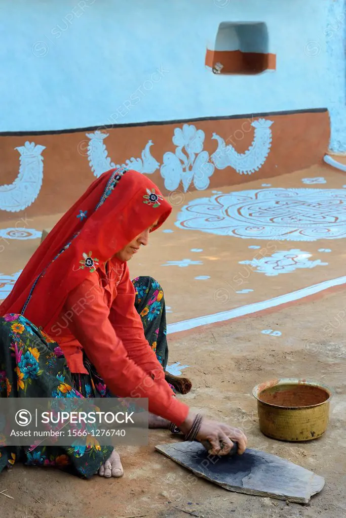 India, Rajasthan, Tonk region, Woman preparing a charcoal powder for painting walls prior to Diwali festival.