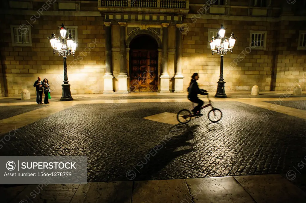 a woman riding a bike in front of the Catalonian Government, Barcelona, Spain.