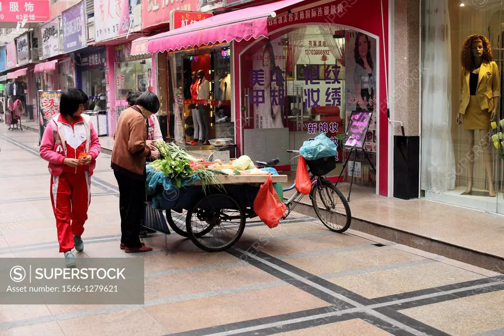 Street scene with illuminated food shop, China