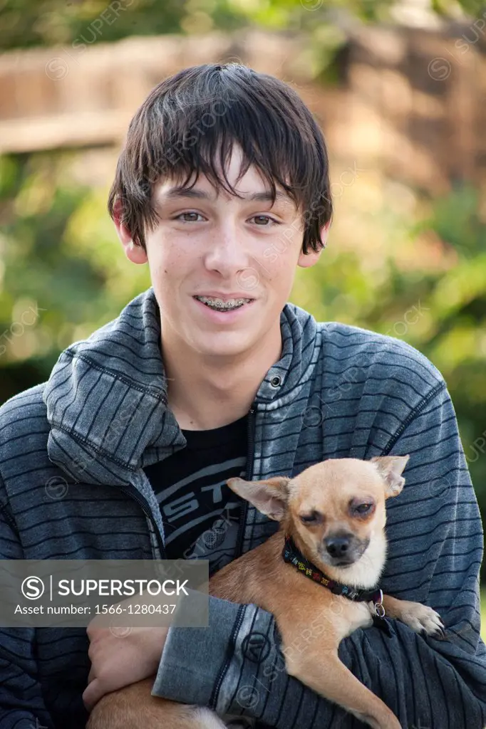 teen boy holding his pet chihuahua looking at the camera