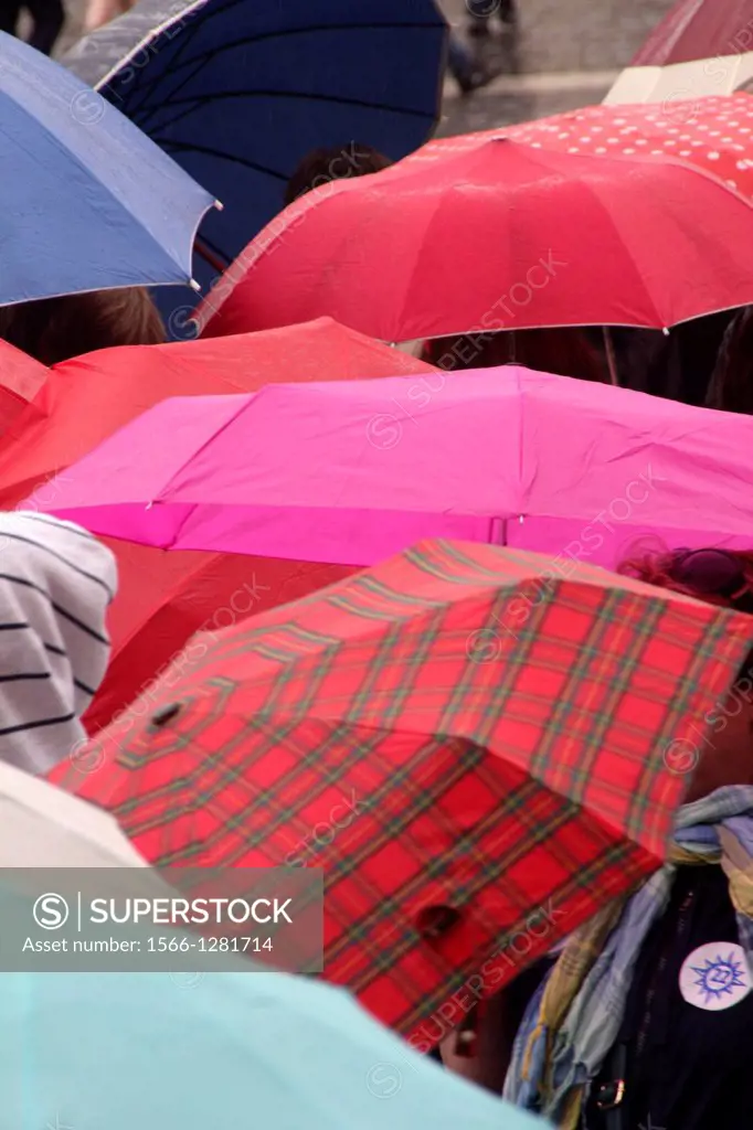 people with umbrellas in saint peter's square, vatican, rome, italy.