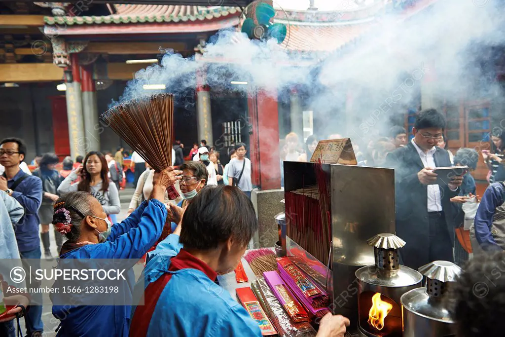 Temple functionaries help worshippers and visitors with incense and ceremonies at the Hsingtian Temple.