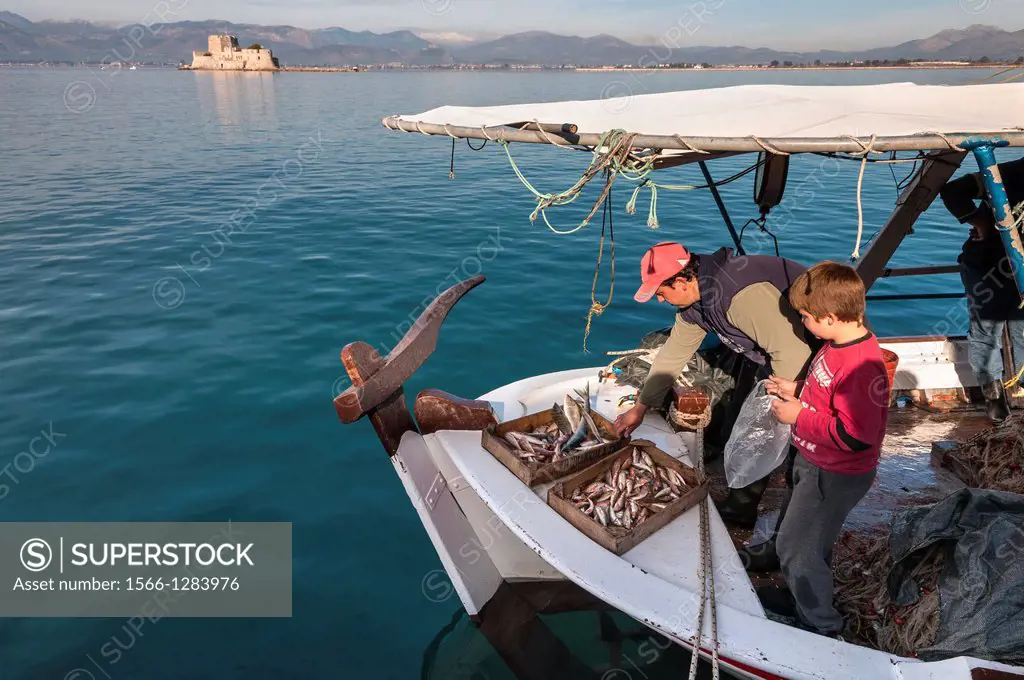 Selling fish from a fishing boat in the harbour at Nafplio with the Bourtzi island and fort in the background, Argolid, Peloponnese, Greece.