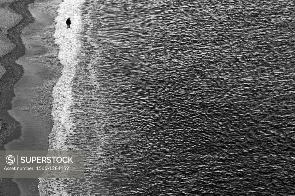Lonely man walking in the water on the beach, Amalfi Coast, Italy, March