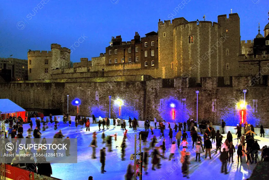 Ice-skating in the moat of the Tower of London in London, UK, during a twilight in the Christmas season.