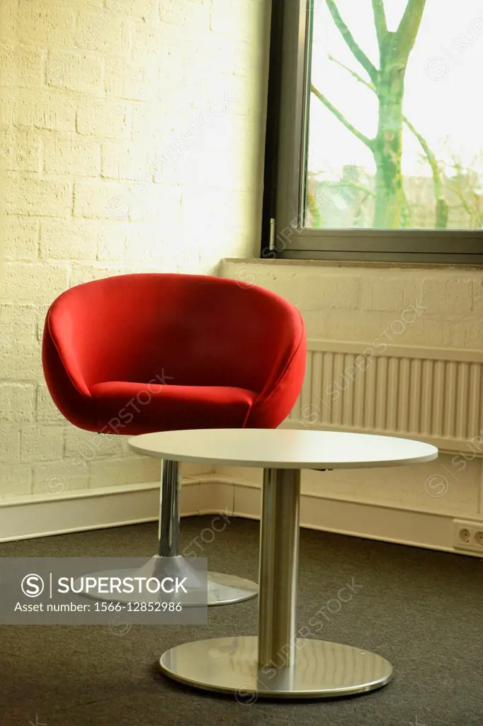 Red chair and small table in corner next to window.